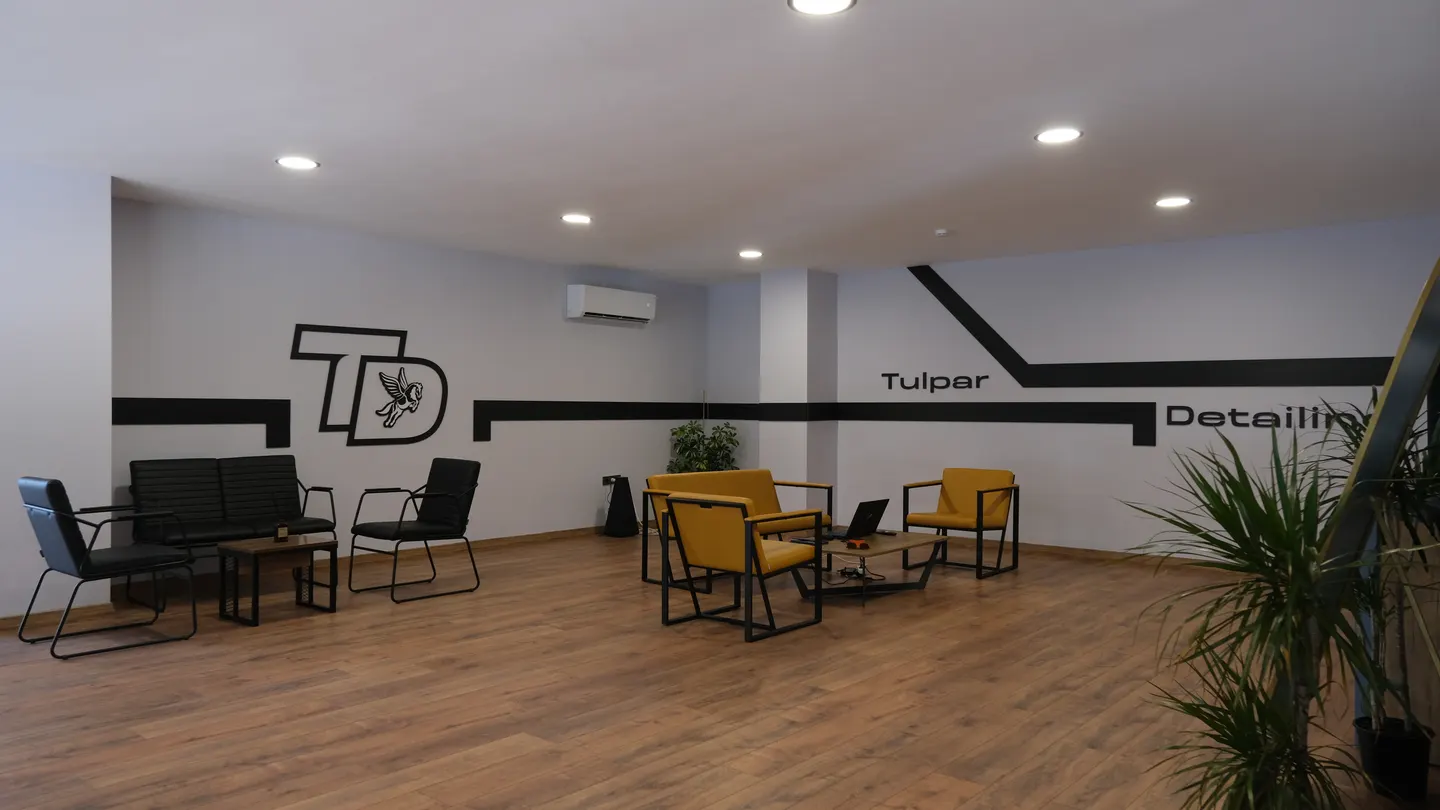 Tulpar Detailing müşteri bekleme alanı, sarı koltuklar ve duvardaki TD logosu