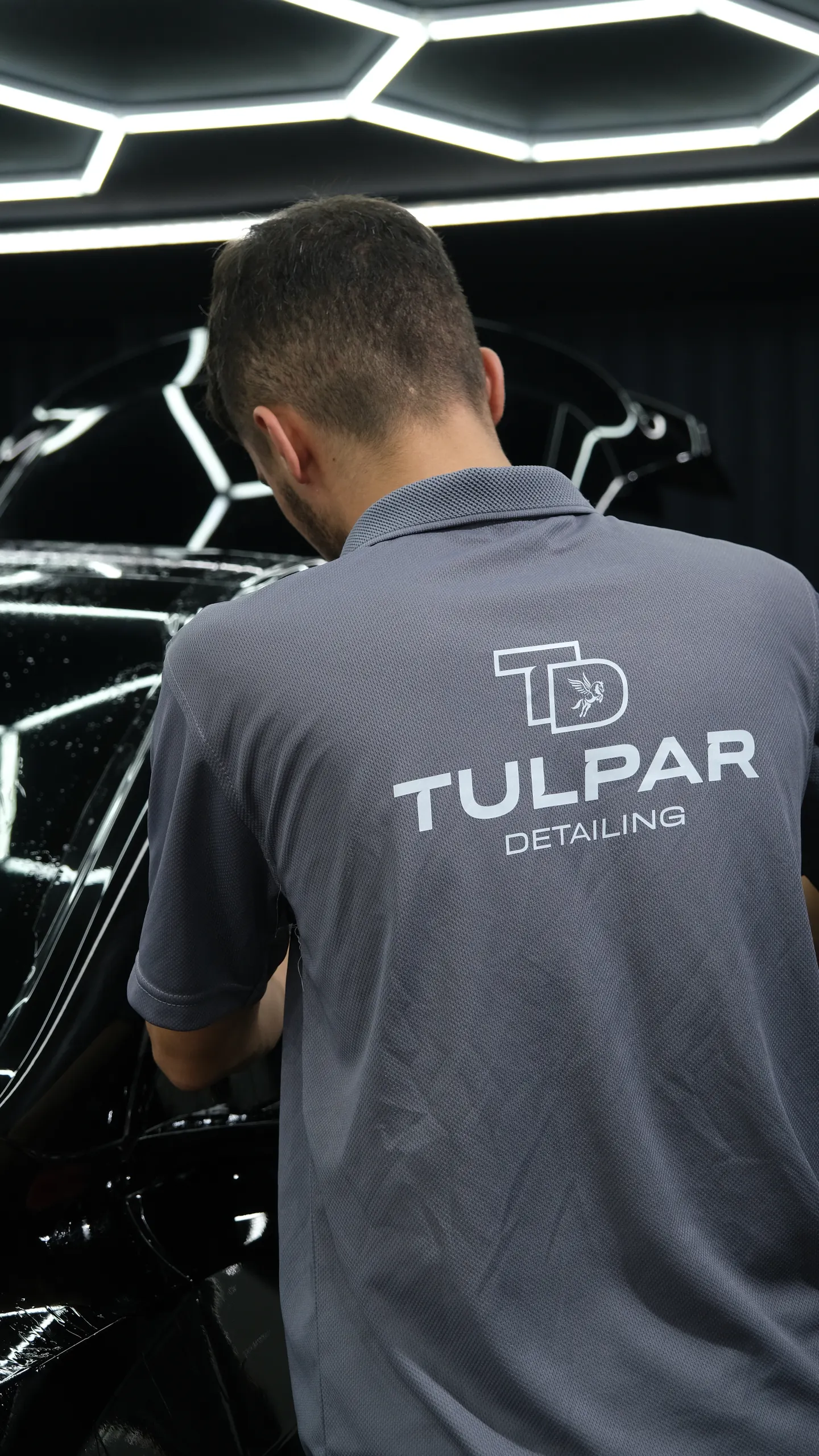 Tulpar Detailing polo tişörtlü teknisyen PPF filmini araç yüzeyine yayıyor