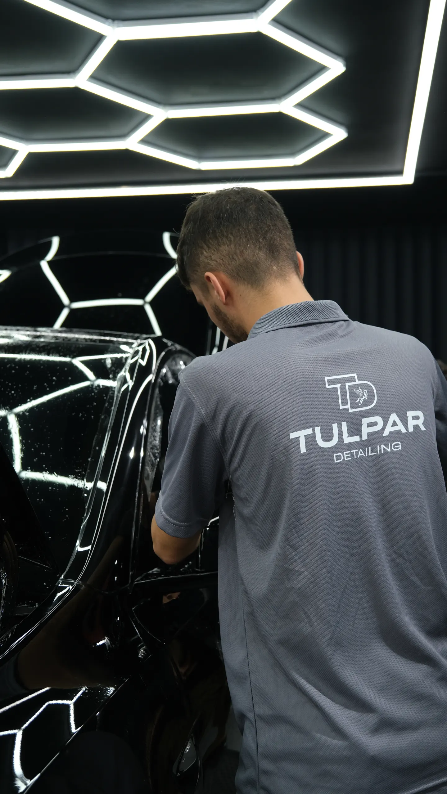 Tulpar Detailing teknisyeni siyah bir aracın kaputuna PPF filmi yerleştiriyor