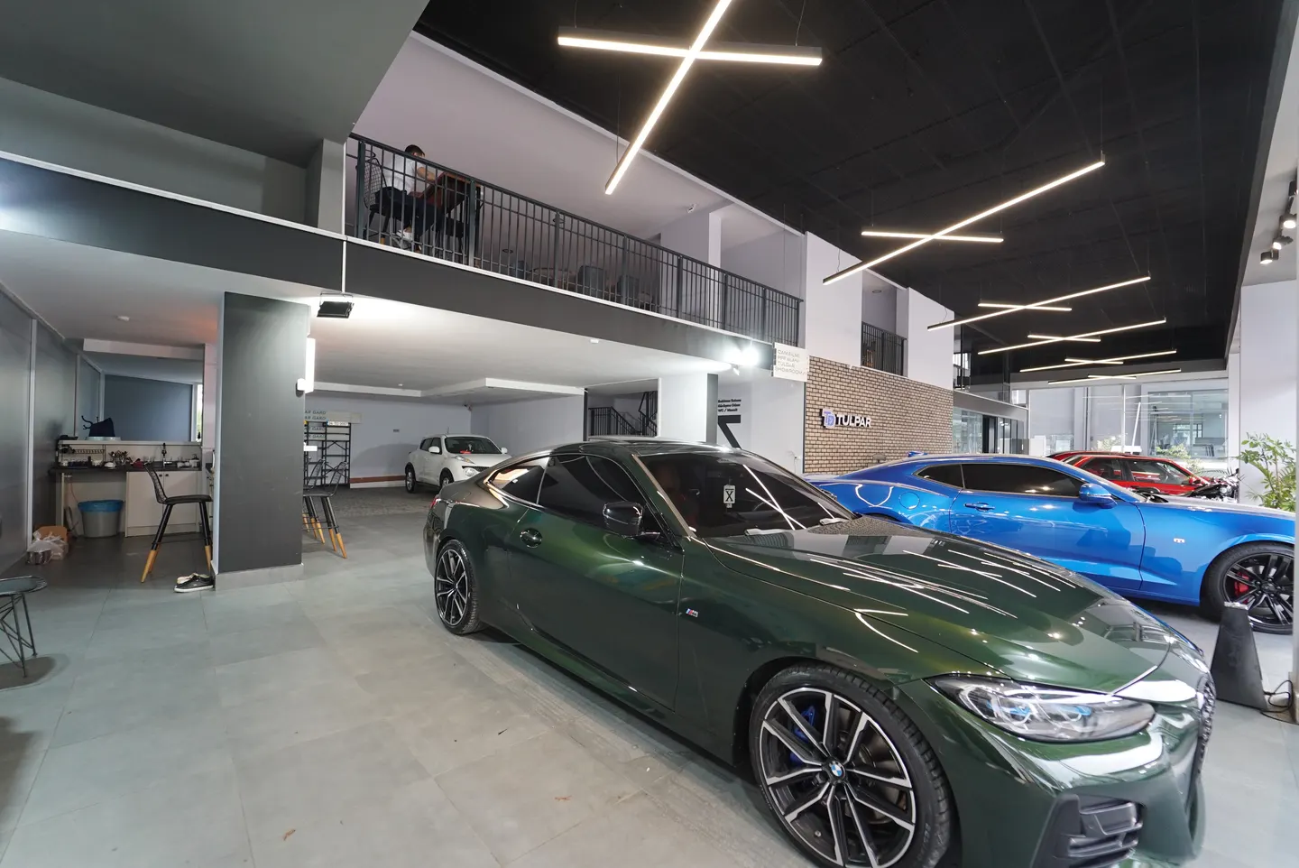 Showroomda sıralanmış yeşil ve mavi BMW araçlar